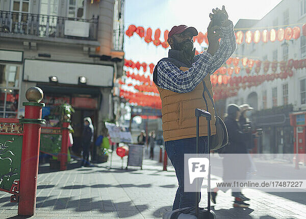 Männlicher Tourist mit Digitalkamera auf einer sonnigen Straße in London  UK
