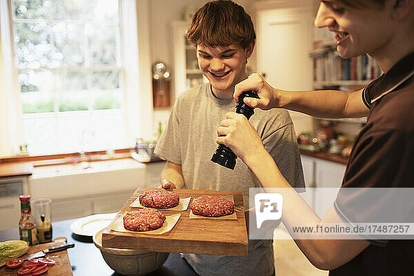 Fröhliche Teenager bereiten in der Küche Hamburger-Patties zu