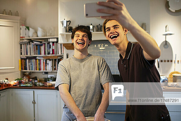 Glückliche Teenager-Jungs lachen und nehmen Selfie in der Küche