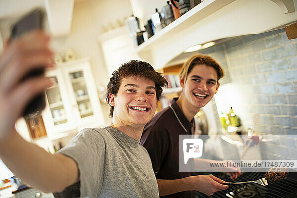 Glückliche Teenager-Jungen nehmen Selfie und Kochen in der Küche