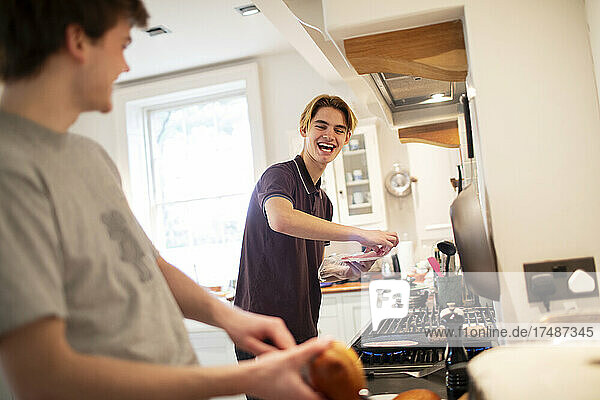 Happy teenage brothers cooking in kitchen