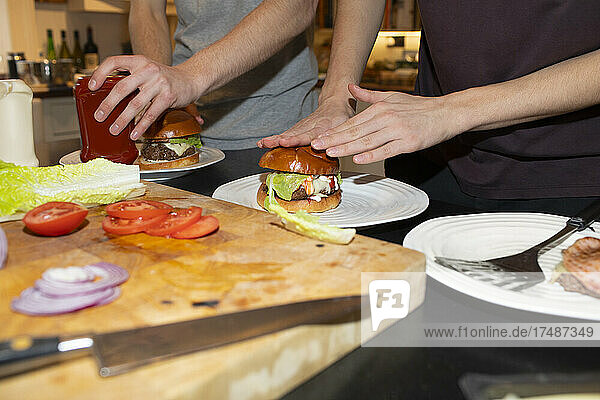 Teenager-Jungen montieren Hamburger in der Küche