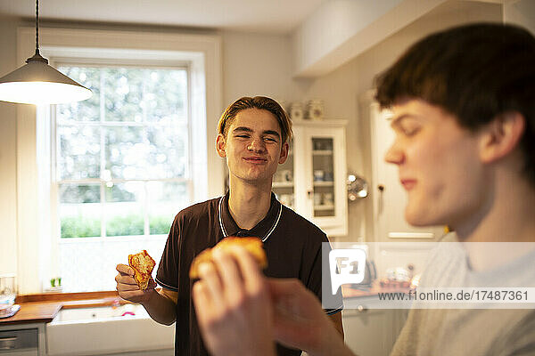 Glückliche Teenager-Jungs essen Pizza in der Küche