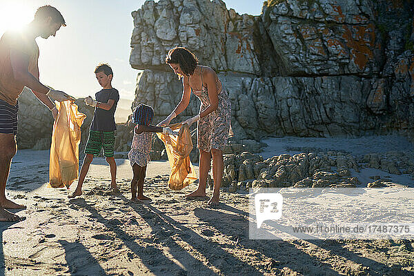 Familie sammelt freiwillig Müll am sonnigen Strand auf