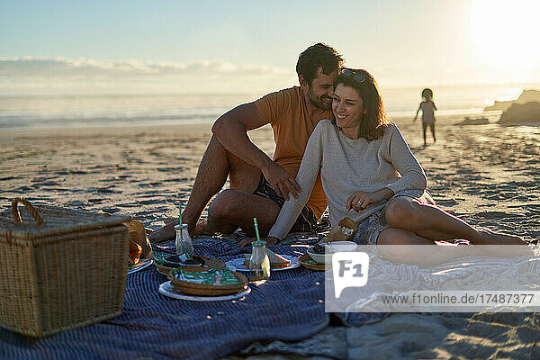 Glückliches  zärtliches Paar beim Picknick am Sommerstrand
