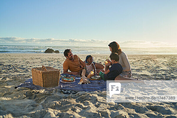 Familie genießt Picknick-Mittagessen am sonnigen Meeresstrand