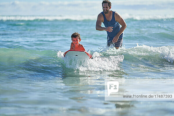 Glücklicher Vater und Sohn beim Bodyboarden im sonnigen Meer