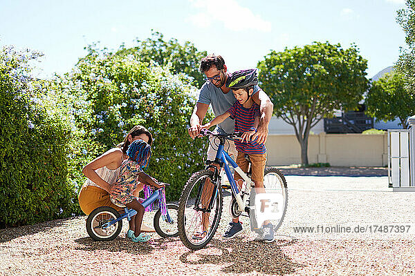 Happy family riding bicycles in sunny driveway