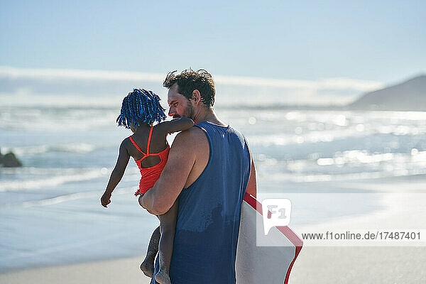 Vater trägt Kleinkind Tochter auf sonnigen Sommer Ozean Strand