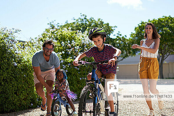 Glückliche Familie beim Fahrradfahren in sonniger Einfahrt
