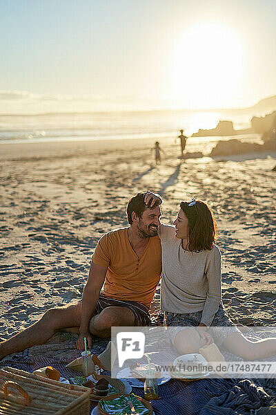 Glückliches  zärtliches Paar beim Picknick am sonnigen Strand
