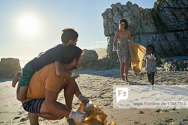 Glückliche Familie beim Müllsammeln am sonnigen Strand