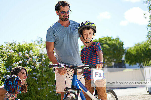 Portrait happy father and son on bicycle in sunny driveway