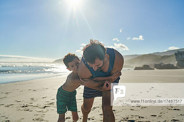 Glücklicher Vater und Sohn umarmen sich am sonnigen Sommerstrand