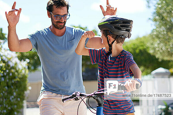 Glücklicher Vater und Sohn auf dem Fahrrad in sonniger Einfahrt