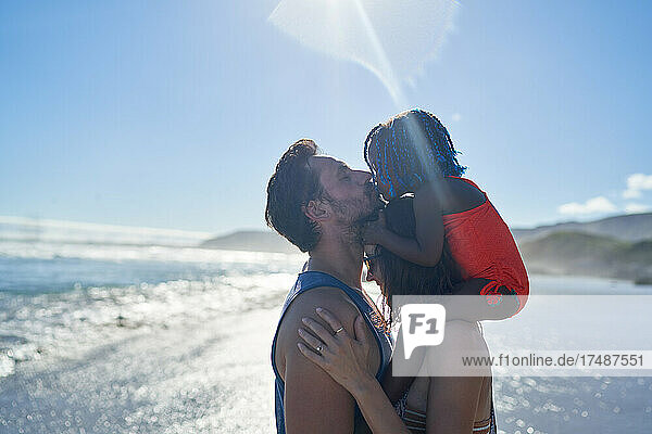 Zärtlicher Vater und Tochter küssen sich am sonnigen Meeresstrand