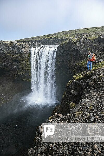 Wanderin mit großen Wanderrucksack vor Wasserfall  Landschaft bei dem Fimmvörðuháls Wanderweg  Südisland  Island  Europa