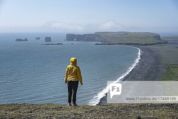 Junge Frau blickt über den Reynisfjara Strand  Schwarzer Sandstrand  Dyrhólaey  Südisland  Island  Europa