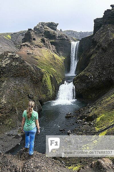 Wanderin vor Wasserfall in einer Schlucht  Landschaft am Fimmvörðuháls Wanderweg  Südisland  Island  Europa