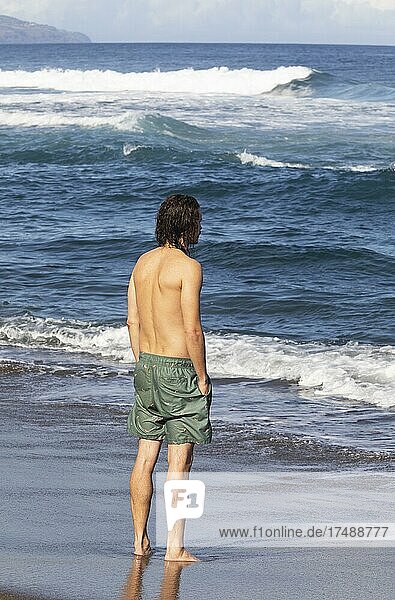Junger Mann steht im Meer am Strand von Praia de Santa Barbara  Ribeira Grande  Insel Sao Miguel  Azoren  Portugal  Europa