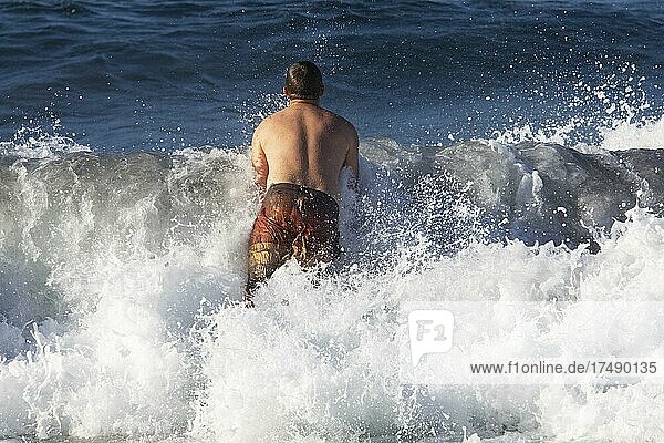 Young man jumps into a high wave on the beach of Praia de Santa Barbara  Ribeira Grande  Sao Miguel Island  Azores  Portugal  Europe