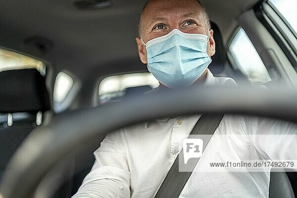 A man in a protective mask driving a car  steering wheel in the foreground  Portugal  Europe