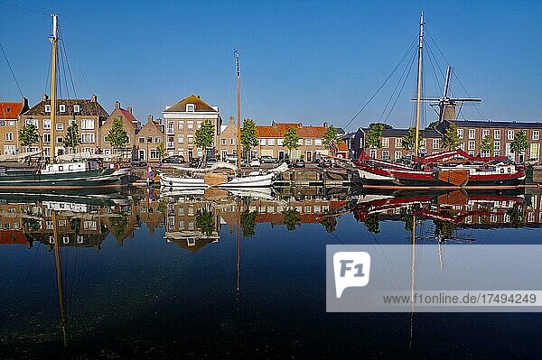 Lte ships  mill and houses reflected in the harbour basin  morning atmosphere  Hellevoetsluis  South Holland  Netherlands