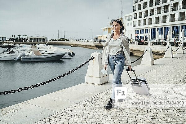 Junge Frau mit Koffer beim Spaziergang in der Stadt  Faro  Portugal  Europa