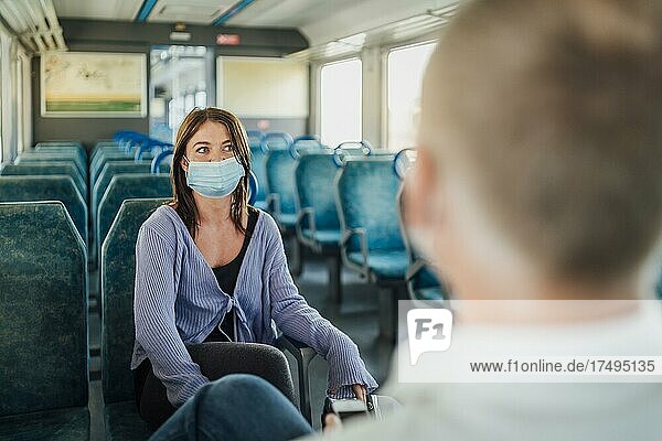 Zwei Reisende mit Maske unterhalten sich in einem Zug  Portugal  Europa