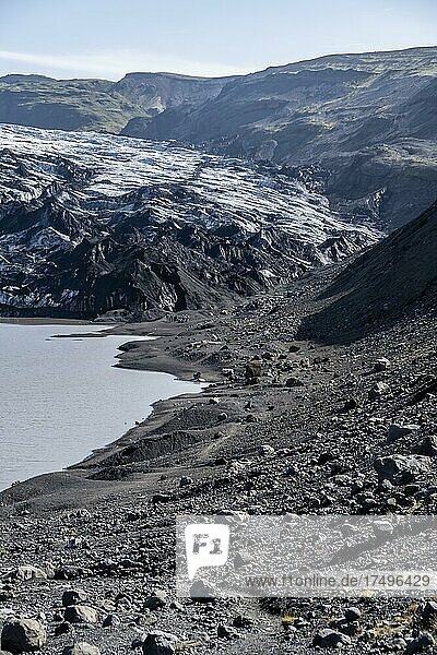 Hiker standing on rocks in front of glacier tongue Sólheimajökull at glacier Mýrdalsjökull  Suðurland  Iceland  Europe