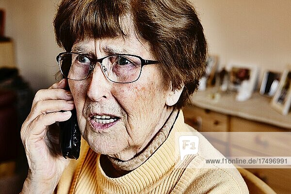 Seniorin zuhause beim Telefonieren schaut erschrocken  Enkeltrick  Köln  Nordrhein-Westfalen  Deutschland  Europa