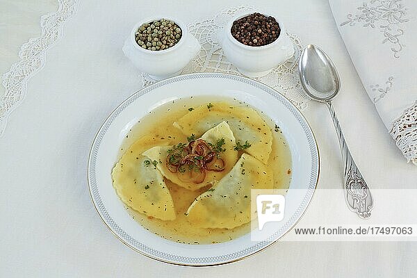 Swabian cuisine  Maultaschen in broth with stewed onion rings  soup plate  spoon.  green and black pepper  Germany  Europe