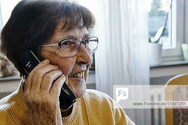 Seniorin zuhause beim Telefonieren mit einem Telefon in der Hand  Köln  Nordrhein-Westfalen  Deutschland  Europa