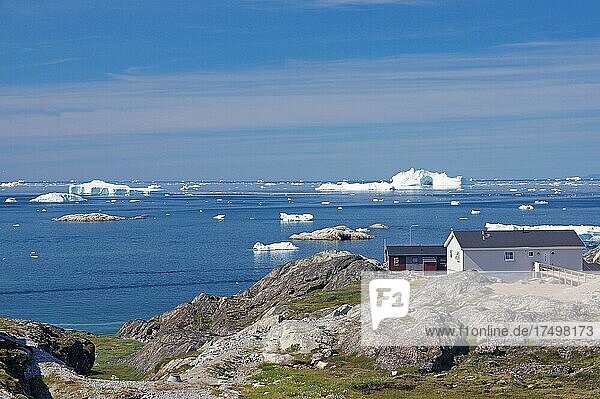 Einfache Wohnhäuser am Rande einer mit Eisbergen bedeckten Bucht  Ilulissat  Arktis  Diskobucht  Grönland  Dänemark  Nordamerika