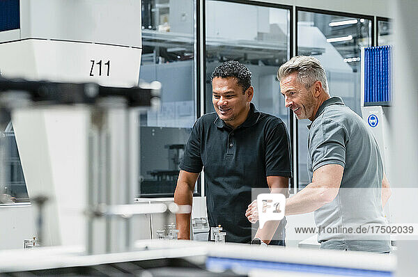 Smiling engineers discussing over automated machinery in factory