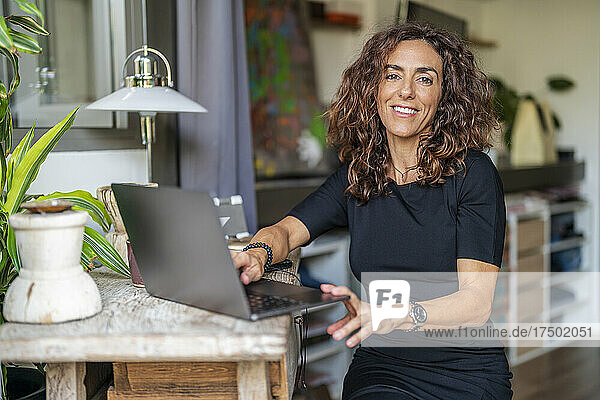 Smiling woman with laptop at home