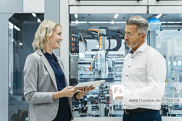 Businesswoman having discussion with coworker at factory