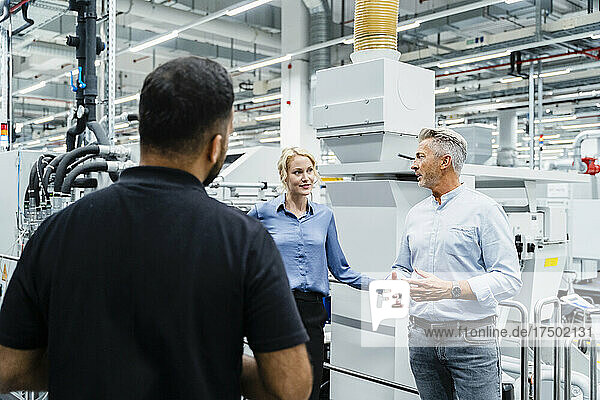 Businessman having discussion with colleagues at industrial machinery