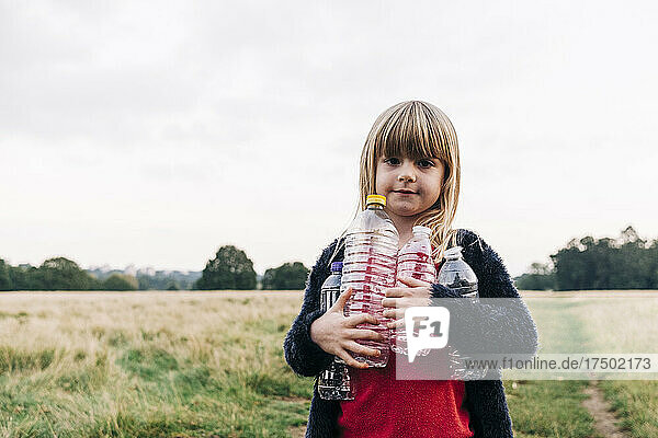 Girl with plastic bottles standing in park
