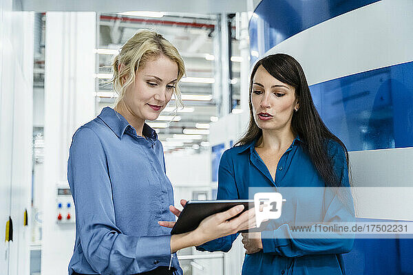 Coworkers discussing over tablet PC at automated industry