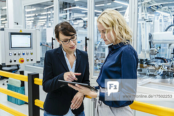 Businesswoman discussing with colleague over tablet PC at factory
