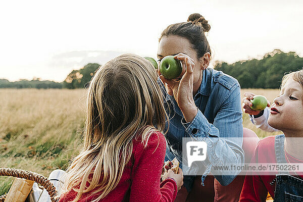 Mother and daughters playing with fruits at park