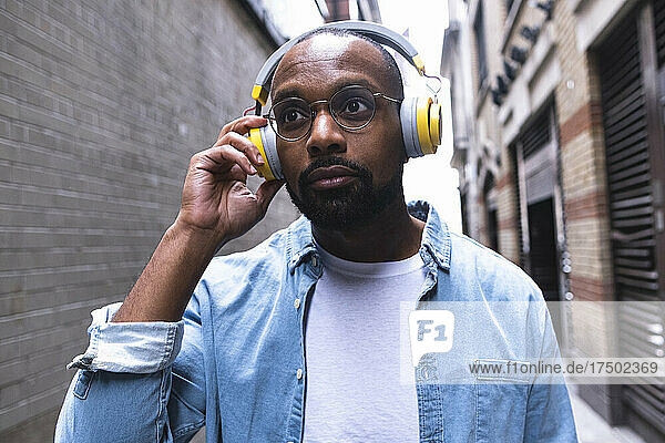 Man with wireless headphones in alley