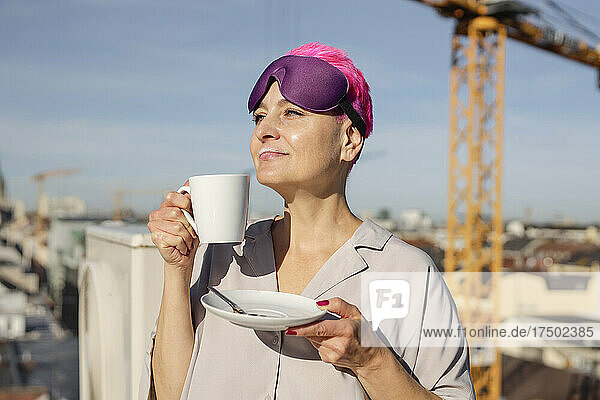 Frau mit Augenmaske trinkt Kaffee an einem sonnigen Tag