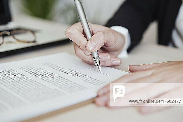 Real estate agent signing document at office