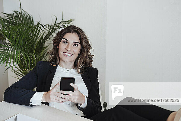Working woman with smart phone smiling at office