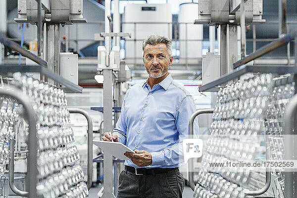 Thoughtful businessman holding tablet PC at industry