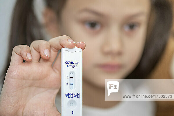 Sad girl holding positive COVID-19 antigen test