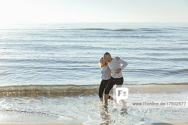 Verspieltes Paar genießt das Wasser am Strand