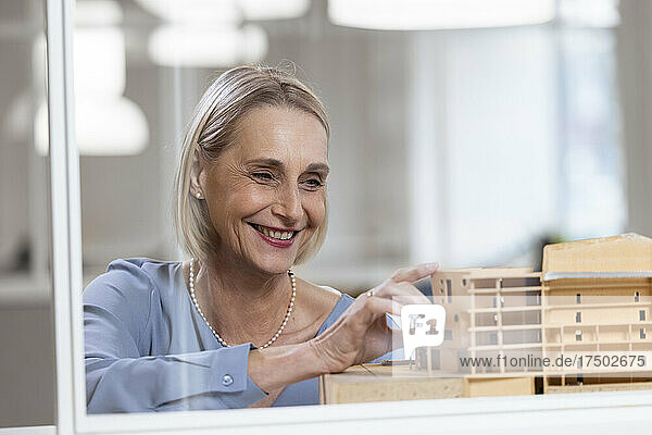 Smiling female architect looking at model in office